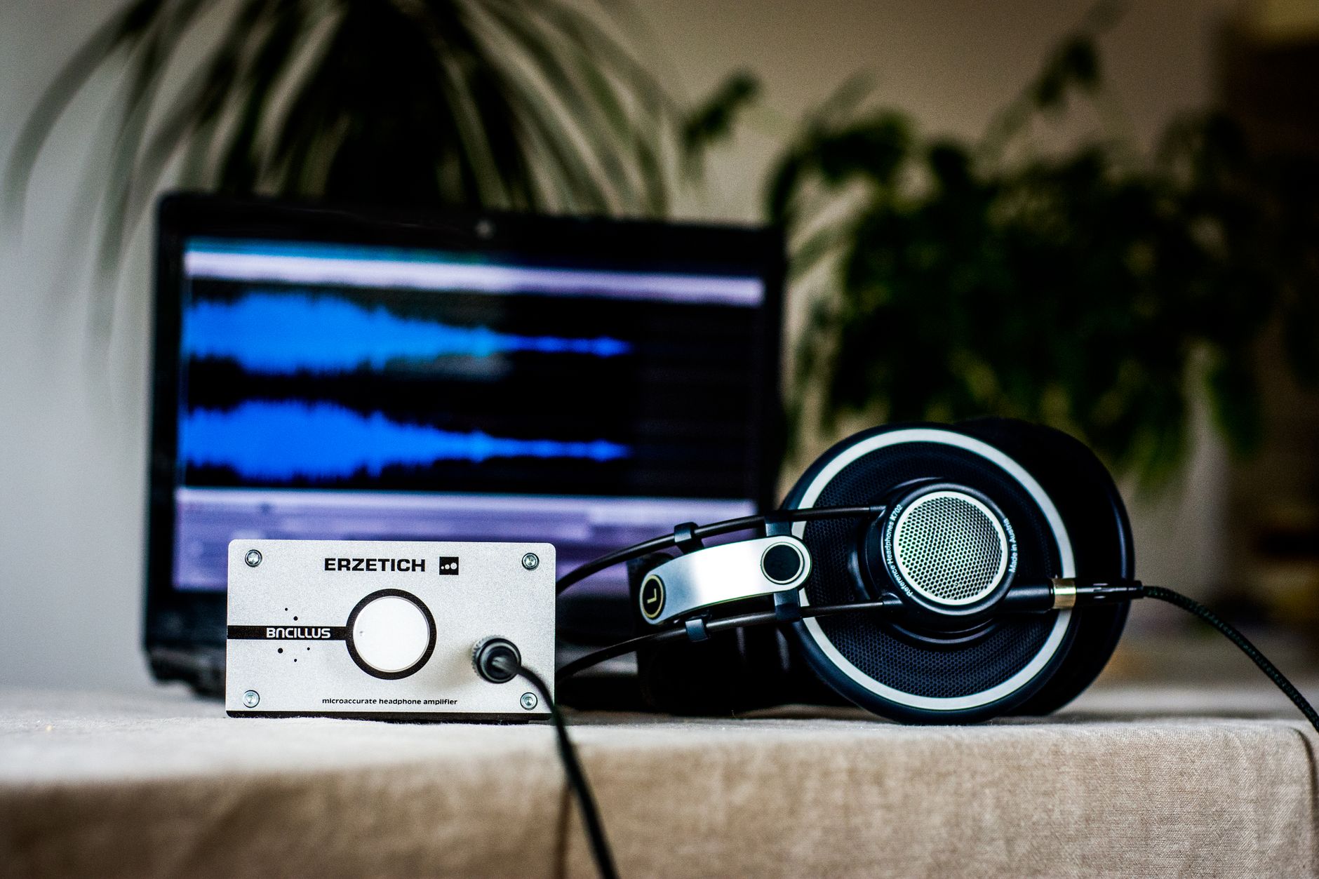 A sleek setup featuring headphones and an amplifier in front of a sound editing laptop, ideal for audio professionals.