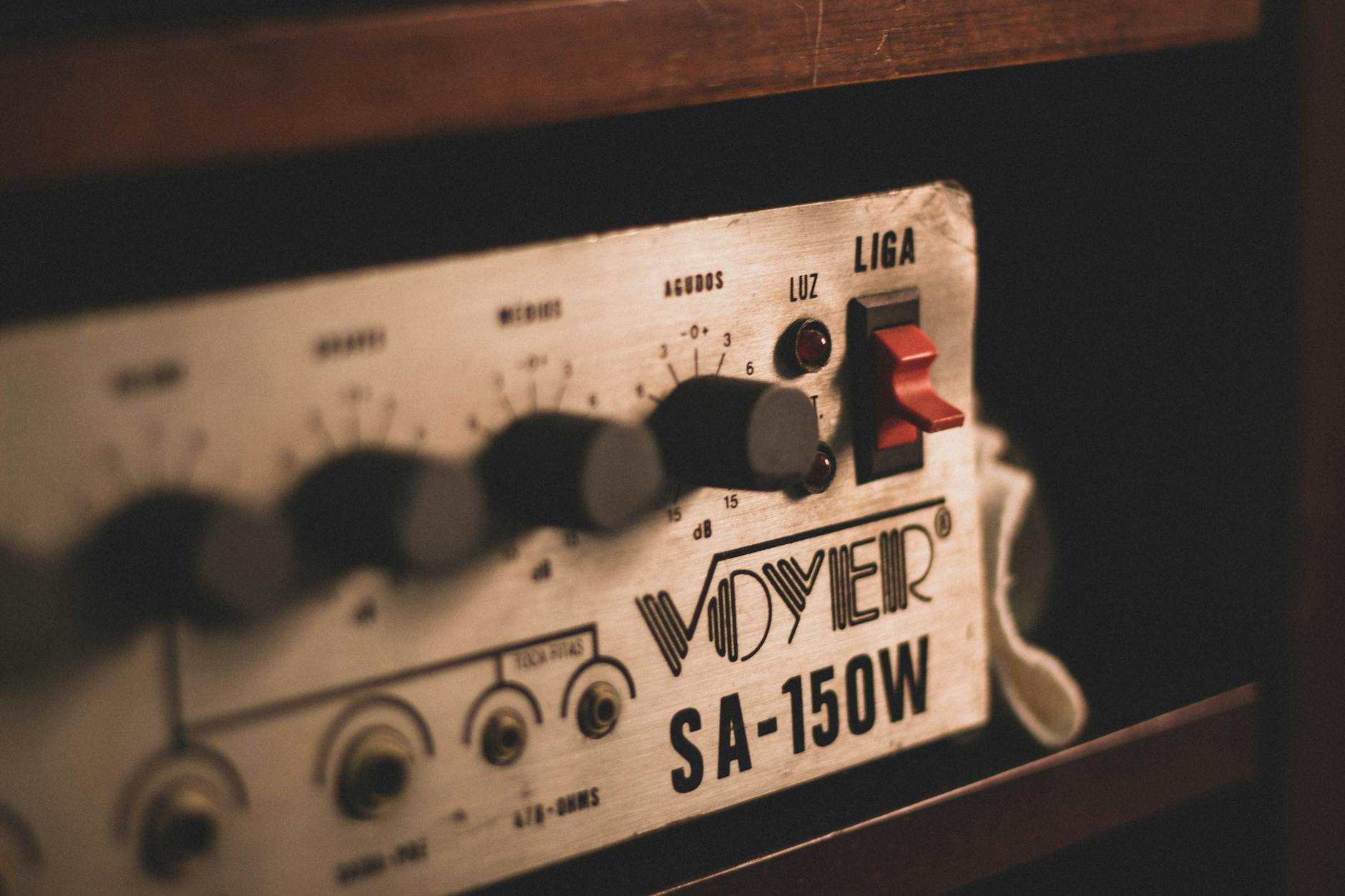 Closeup of old electronic audio equipment amplifier with metal control panel placed in cabinet